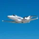 White private jet in flight against a clear blue sky