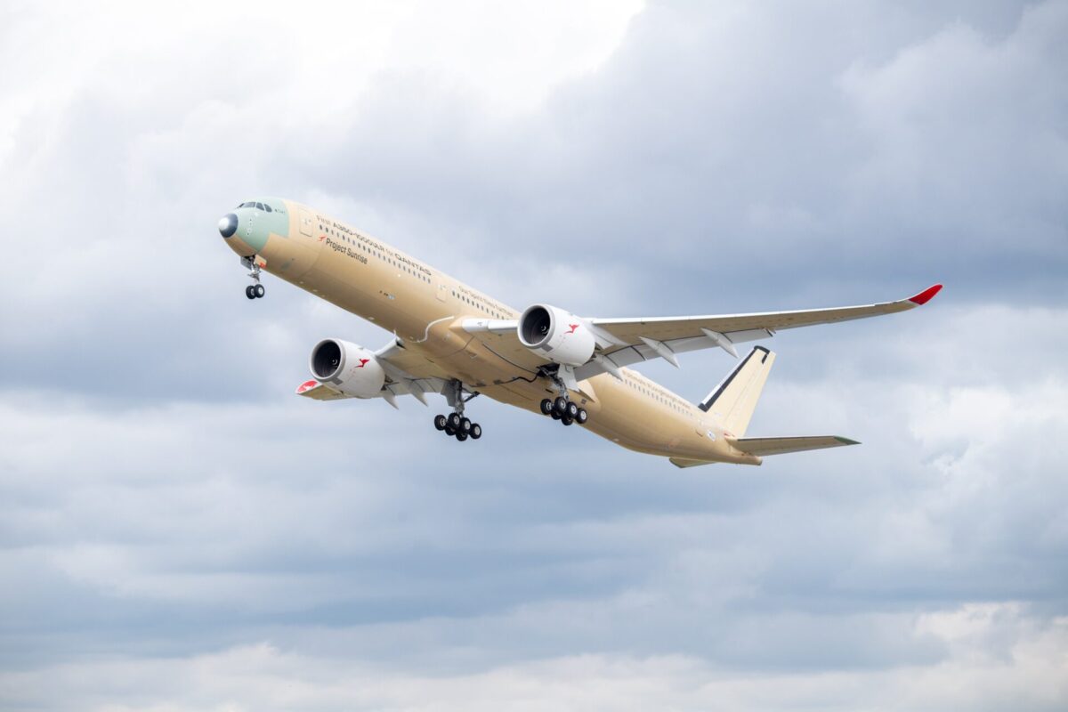 first flight of the qantas a350 1000ulr msn 707 Beige passenger jet with red wingtip climbs into a cloudy sky during takeoff landing gear down