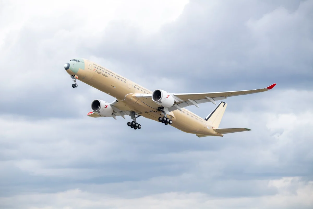 first flight of the qantas a350 1000ulr msn 707 Beige passenger jet with red wingtip climbs into a cloudy sky during takeoff landing gear down