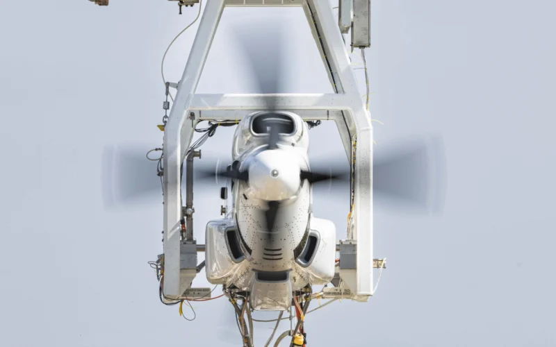 Front view of a propeller driven aircraft engine mounted in a metal test rig blades spinning blur