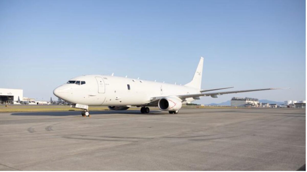 image White commercial airplane on a taxiway at an airport with hangars in the distance and a clear blue sky