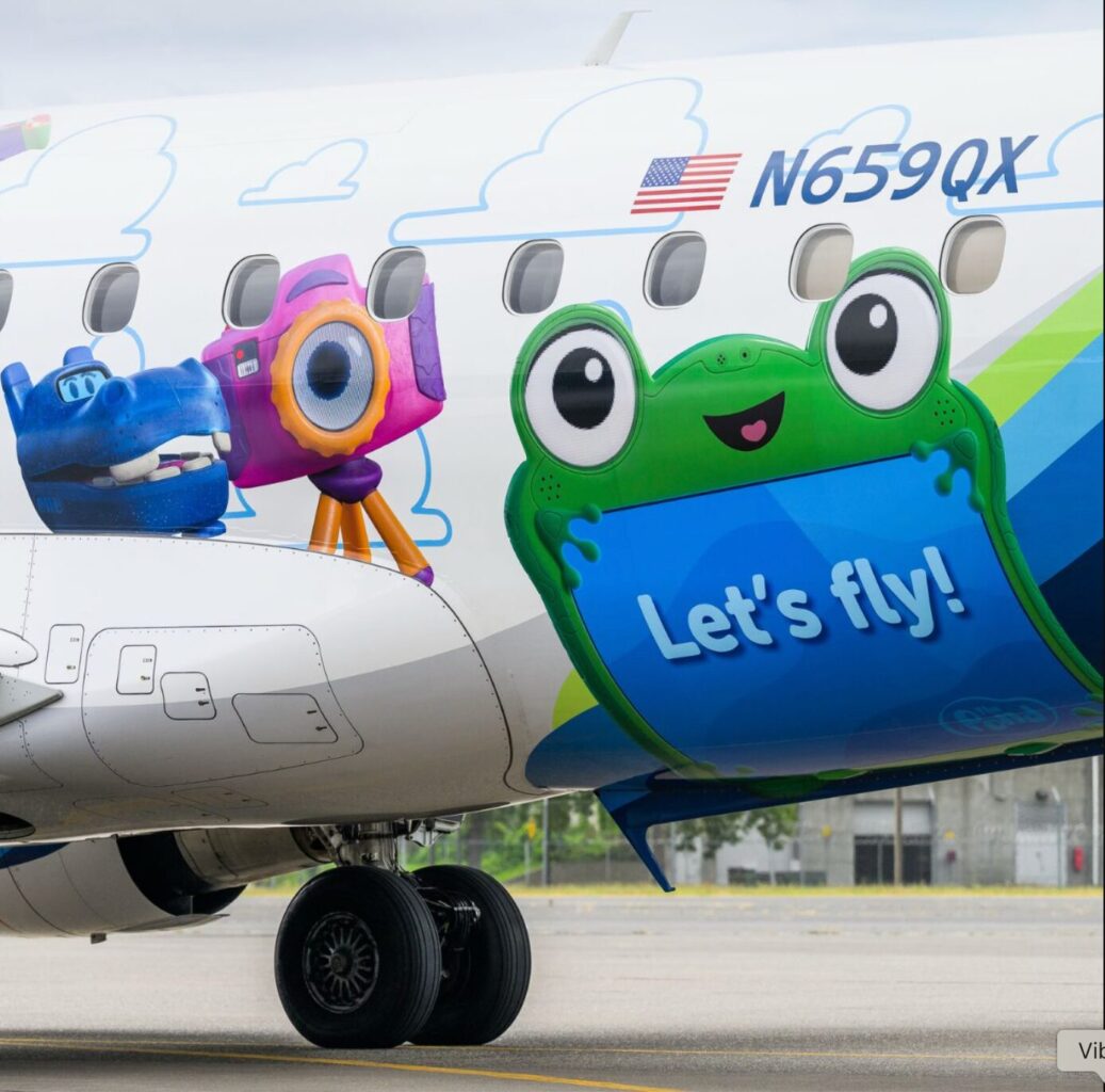 image Airplane fuselage with colorful cartoon characters and the slogan Lets fly including a green frog like character and purple camera character