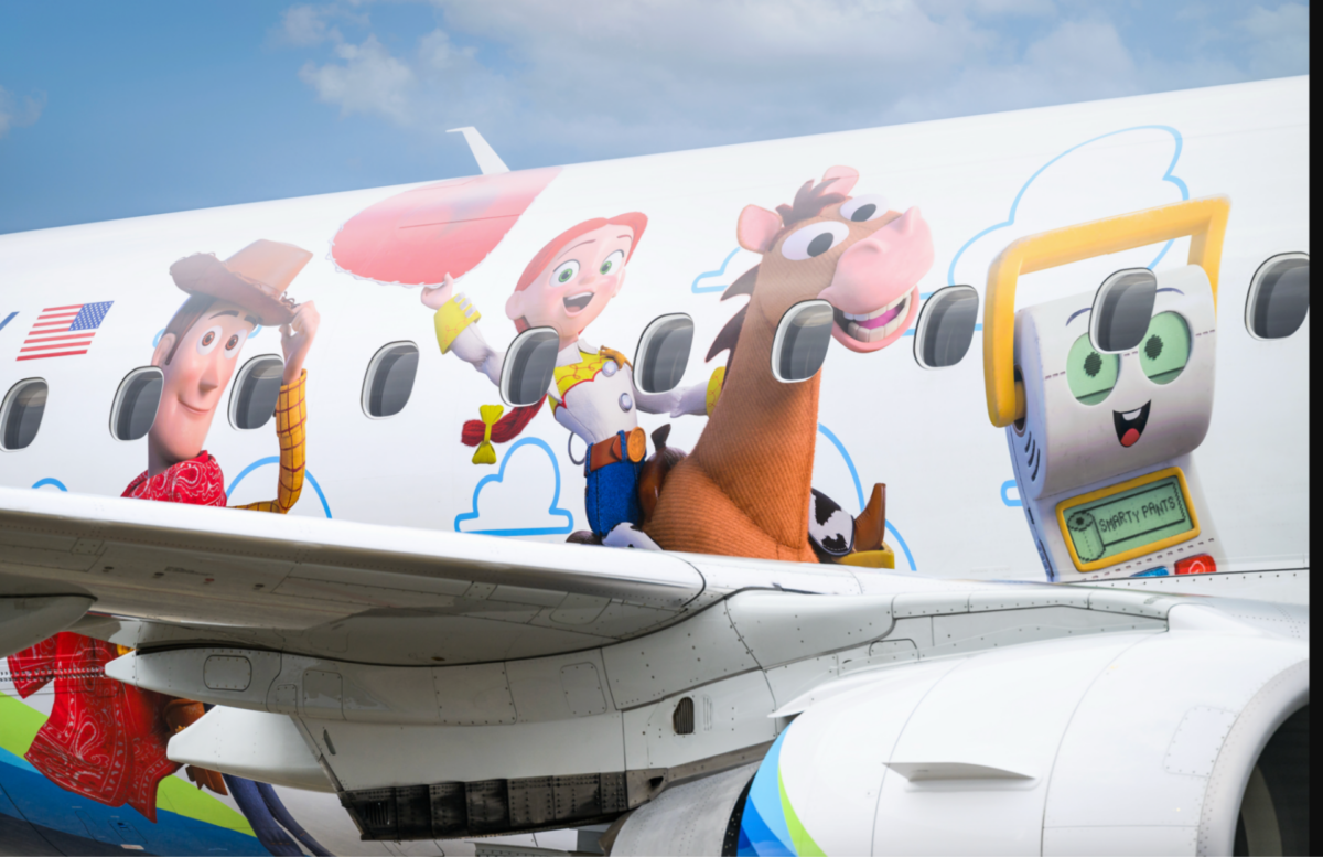image Airplane fuselage decorated with Toy Story characters Woody Jessie Bullseye and a smiling computer themed graphic against a blue sky