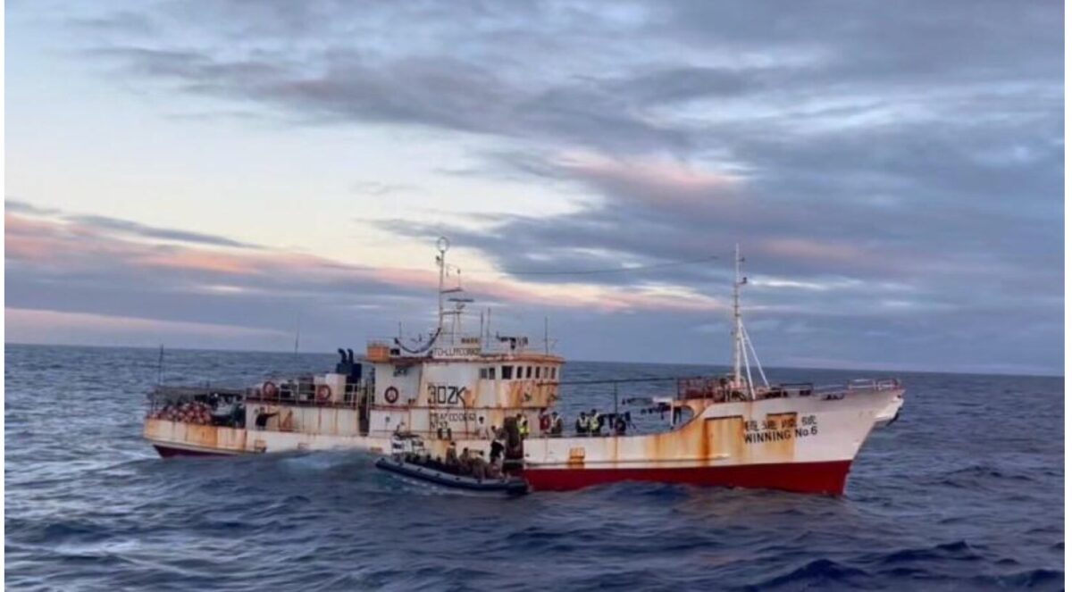 image Rusty white and red fishing boat named Winning No6 on the open sea at sunset with people on deck and a small inflatable boat nearby