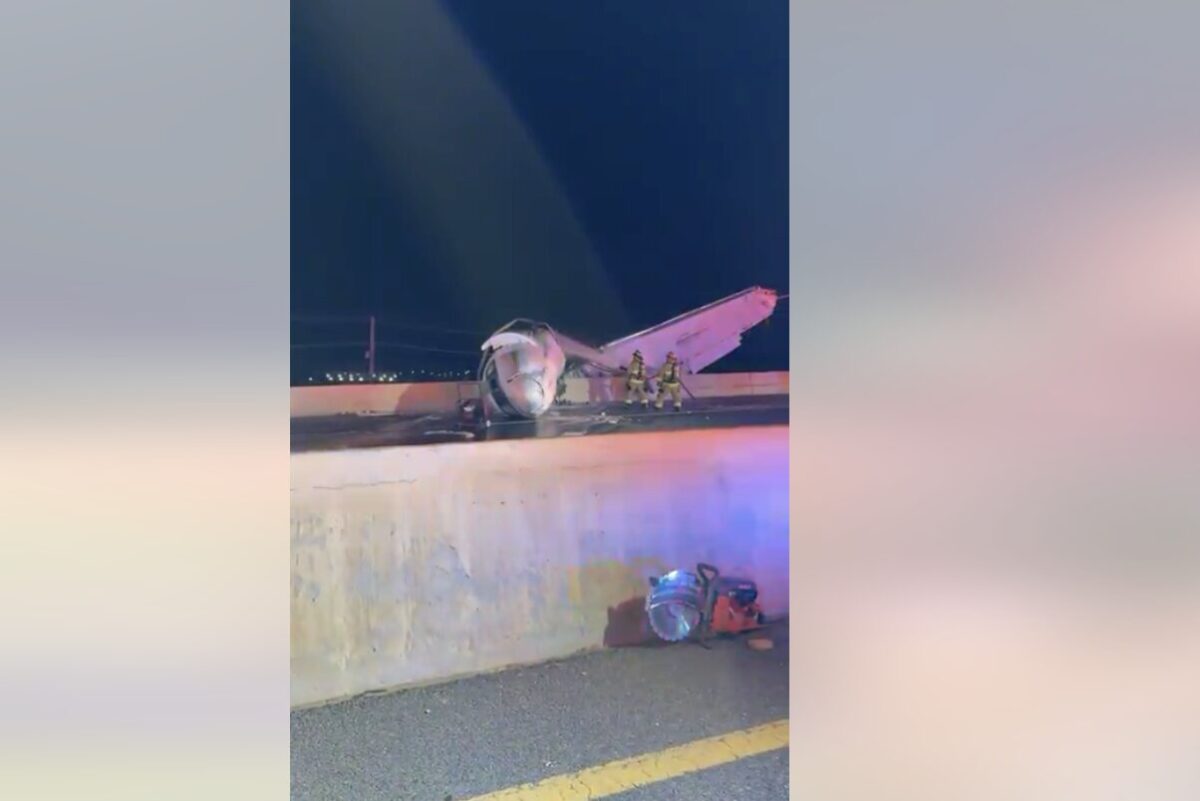 laredo crash snap Night scene of a crashed small airplane on a highway barrier with firefighters examining the wreckage and debris on the roadlighted by emergency vehicles