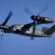 Bell V 280 Valor tiltrotor aircraft in flight rotors blurred against a clear blue sky