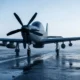 Front view of a propeller driven military aircraft on a wet runway