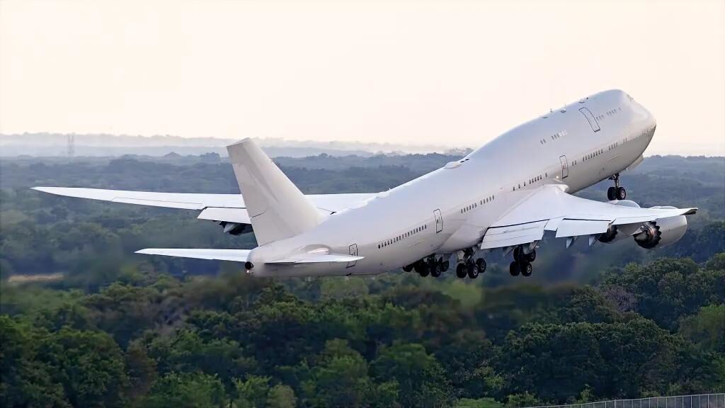 qataraf1 A large white commercial jet climbs off the runway with its landing gear still extended over a green forested landscape