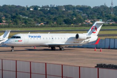 Paranair regional jet on the tarmac white fuselage with blue logo and red tail emblem registration ZP CRS orange cones nearby fence in foreground