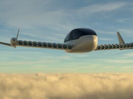 Futuristic jet with dozens of engine pods along its swept wings flying above clouds at sunset