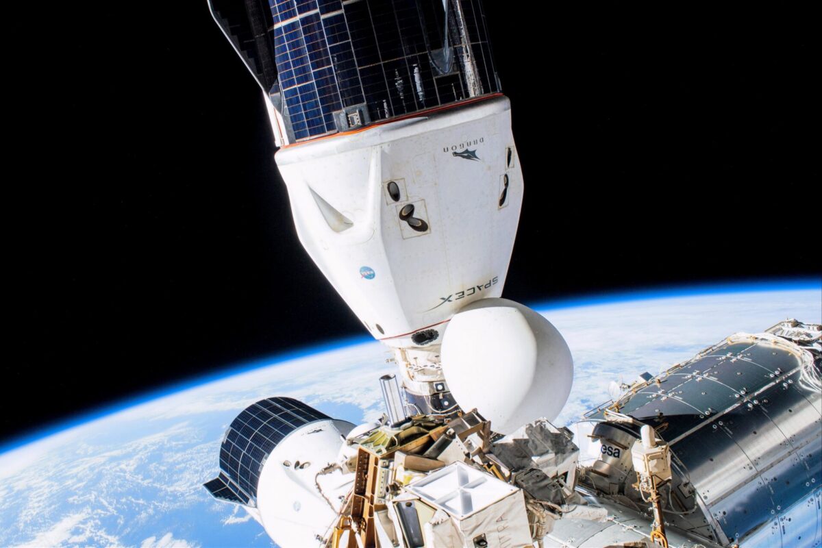 Space shuttle in orbit attached to a space station with Earths curving horizon below and solar panels visible against black space