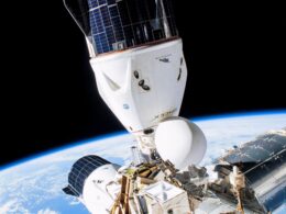 Space shuttle in orbit attached to a space station with Earths curving horizon below and solar panels visible against black space