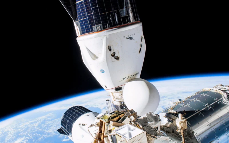 Space shuttle in orbit attached to a space station with Earths curving horizon below and solar panels visible against black space