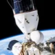 Space shuttle in orbit attached to a space station with Earths curving horizon below and solar panels visible against black space