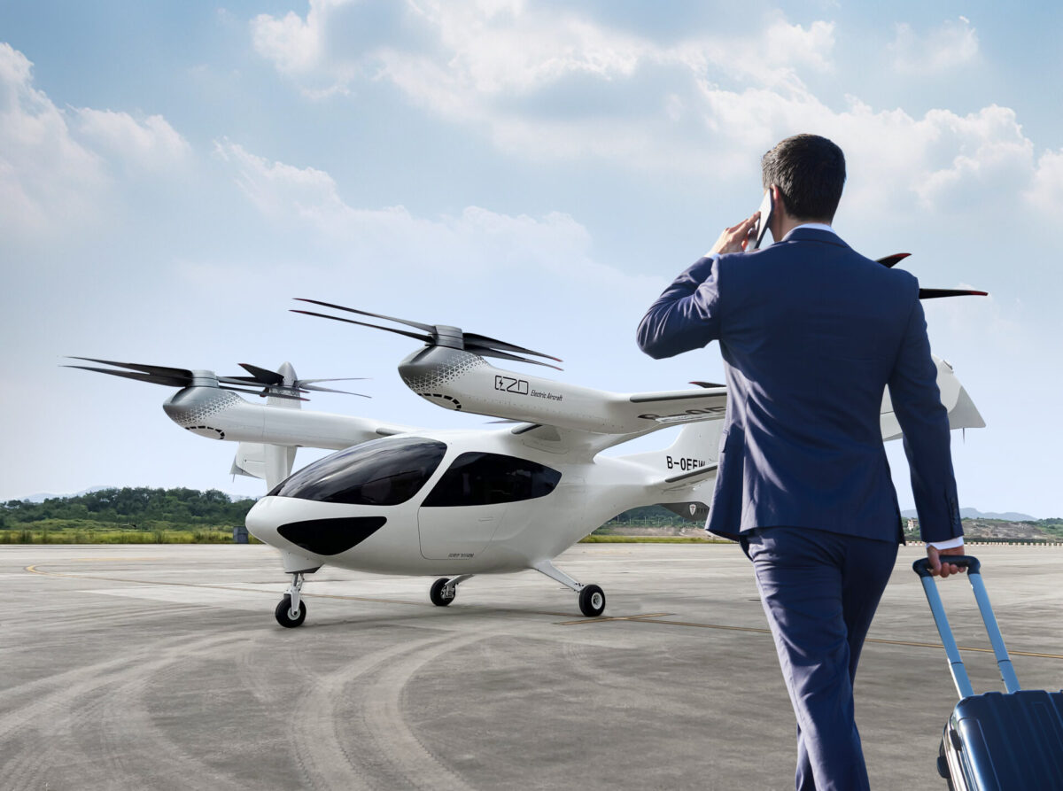 微信图片 20260618135919 3499 88 Businessman in a blue suit on a runway talking on his phone beside a white electric aircraft with multiple propellers