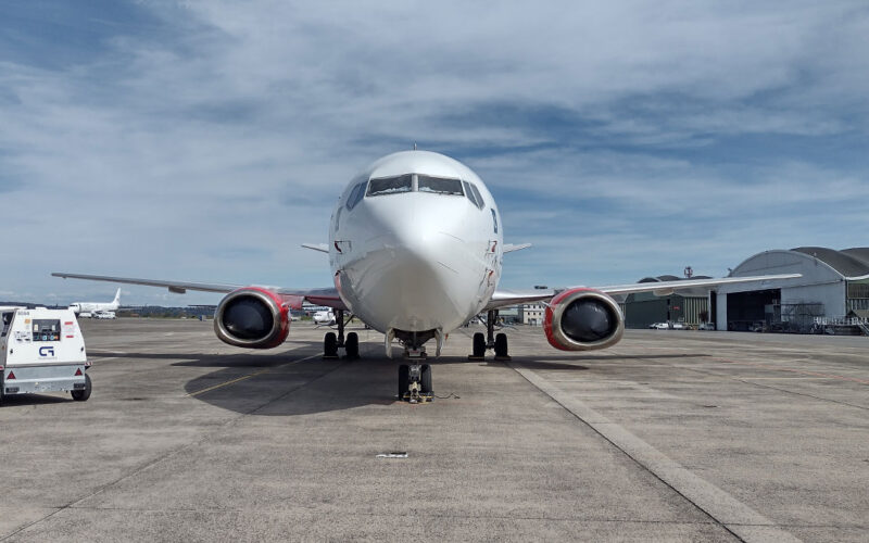 001 2 Front view of a white passenger jet on taxiway with red engine nacelles and ground equipment nearby