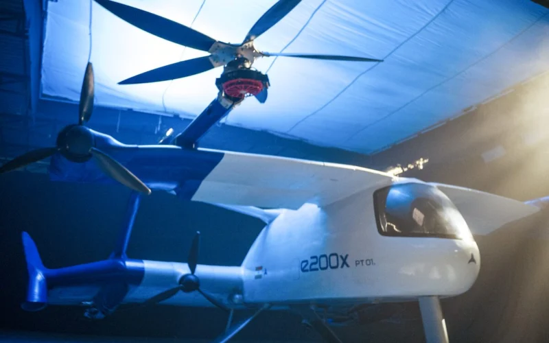 White e2000X PT01 tilt rotor aircraft inside a blue lit hangar rotors extended above the fuselage
