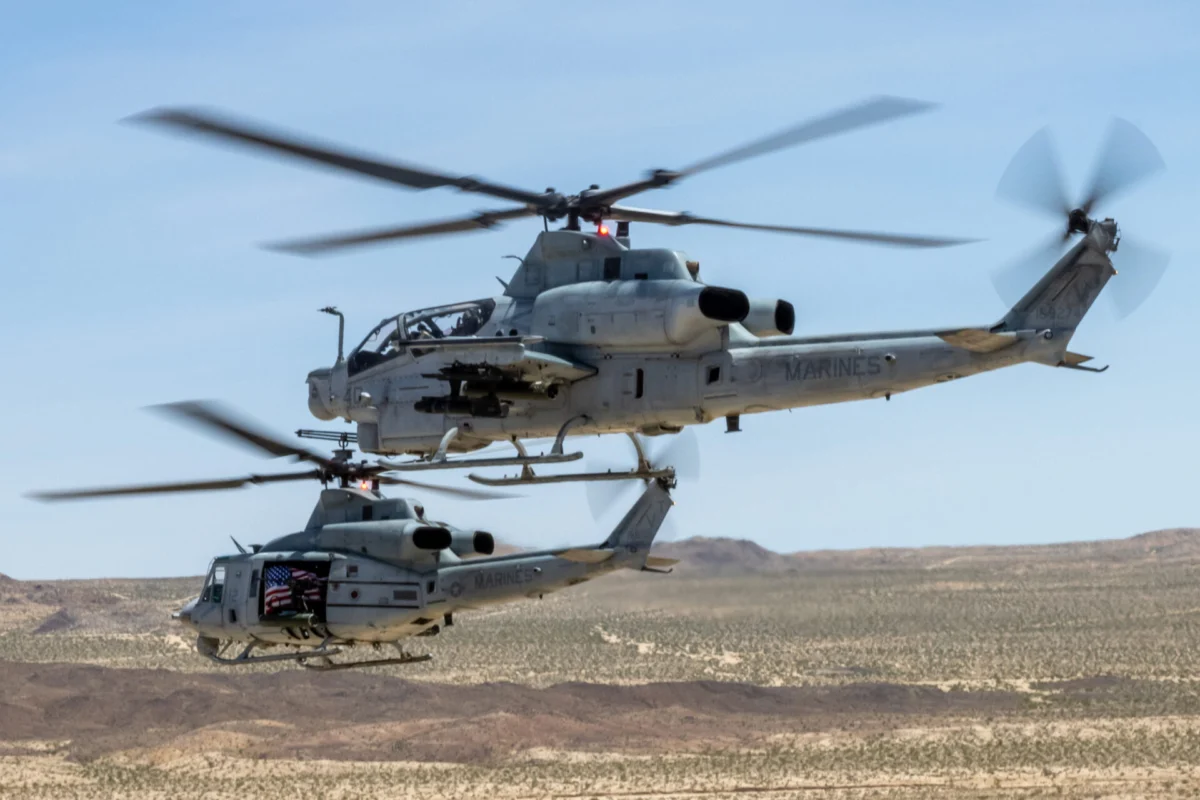 Two US Marines helicopters in flight over a barren desert landscape rotor blades blurred from motion