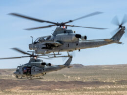Two US Marines helicopters in flight over a barren desert landscape rotor blades blurred from motion