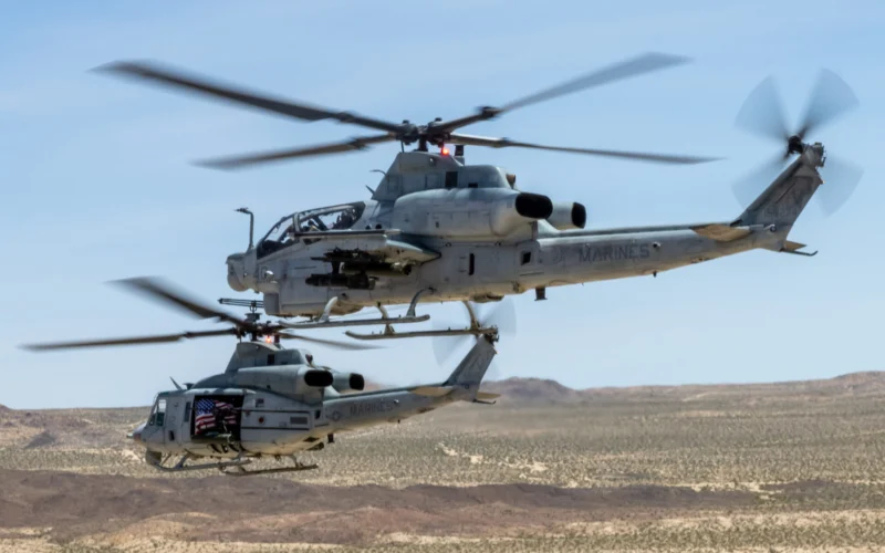 Two US Marines helicopters in flight over a barren desert landscape rotor blades blurred from motion