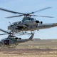 Two US Marines helicopters in flight over a barren desert landscape rotor blades blurred from motion