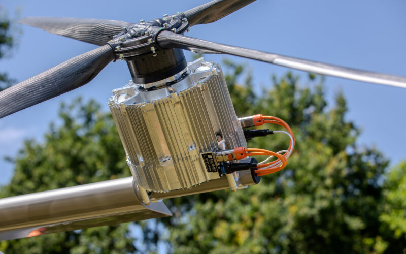 A84A9421 1 Close up of a carbon fiber rotor hub with a silver finned power electronics unit and orange cables outdoors