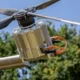 Close up of a carbon fiber rotor hub with a silver finned power electronics unit and orange cables outdoors