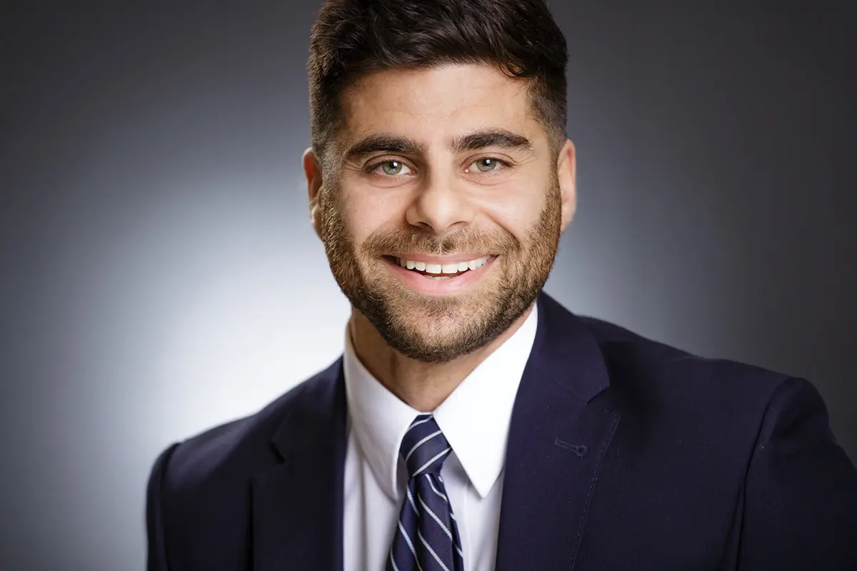 AJ Abedin Avia Solutions Group Professional headshot of a smiling man in a navy suit and striped tie against a neutral gradient background