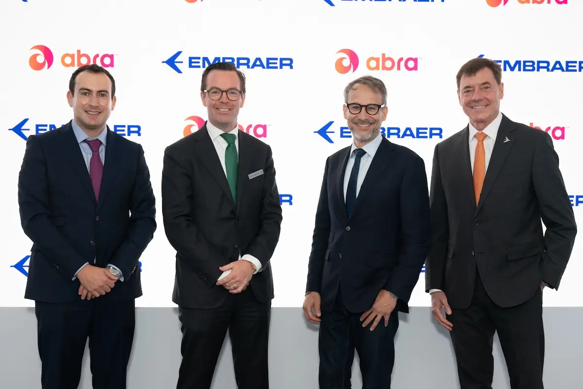 Abra Group Announces an Agreement to Purchase up to 45 E195 E2 Aircraft from Embraer Providing Additional Flexibility to Abras Growth and Connectivity Strategy Four executives in dark suits pose for a photo in front of a white branded backdrop with Embraer and Abra logos smiling