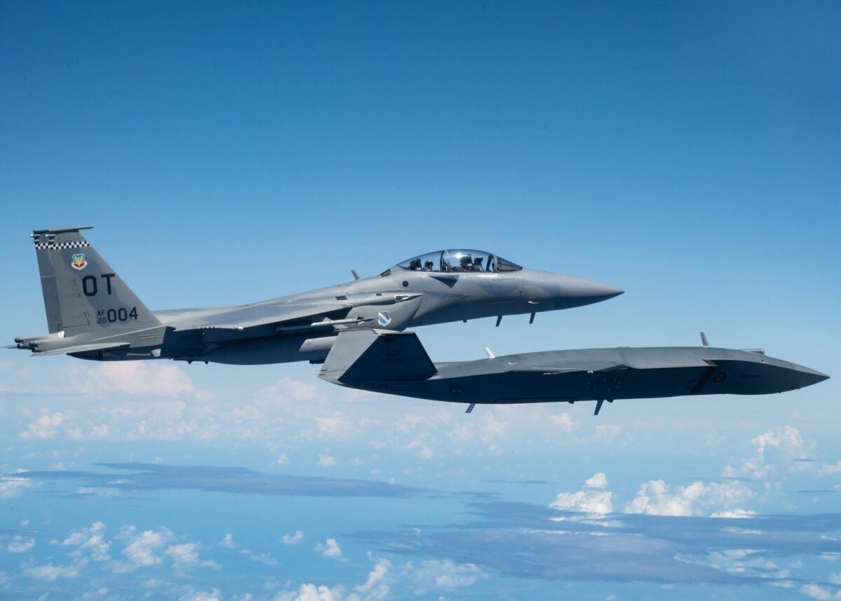 An MQ 28 Ghost Bat and US Air Force F 15EX Eagle II participated in Exercise Valiant Shield 2026 2 Two seat fighter jet in flight against a clear blue sky showing tail markings and checkerboard pattern on the tail