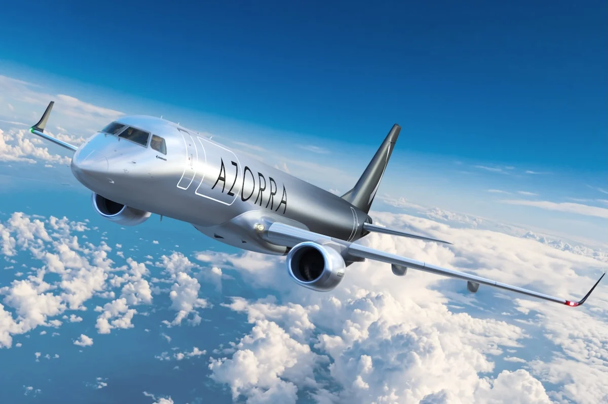 BlueSkyWithCloudsAndSunOnAirplaneView Silver passenger jet flying above fluffy clouds with AZORRA branding on the fuselage cruising in clear blue sky