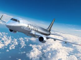 Silver passenger jet flying above fluffy clouds with AZORRA branding on the fuselage cruising in clear blue sky