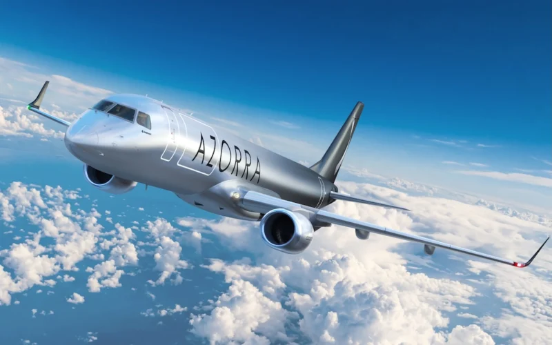 Silver passenger jet flying above fluffy clouds with AZORRA branding on the fuselage cruising in clear blue sky