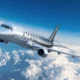Silver passenger jet flying above fluffy clouds with AZORRA branding on the fuselage cruising in clear blue sky