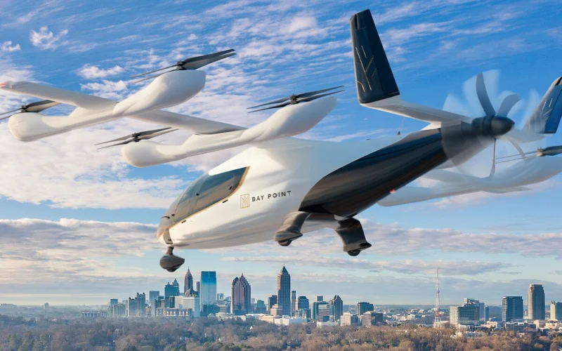 Futuristic white VTOL flying car labeled Bay Point hovering over a city skyline on a clear day