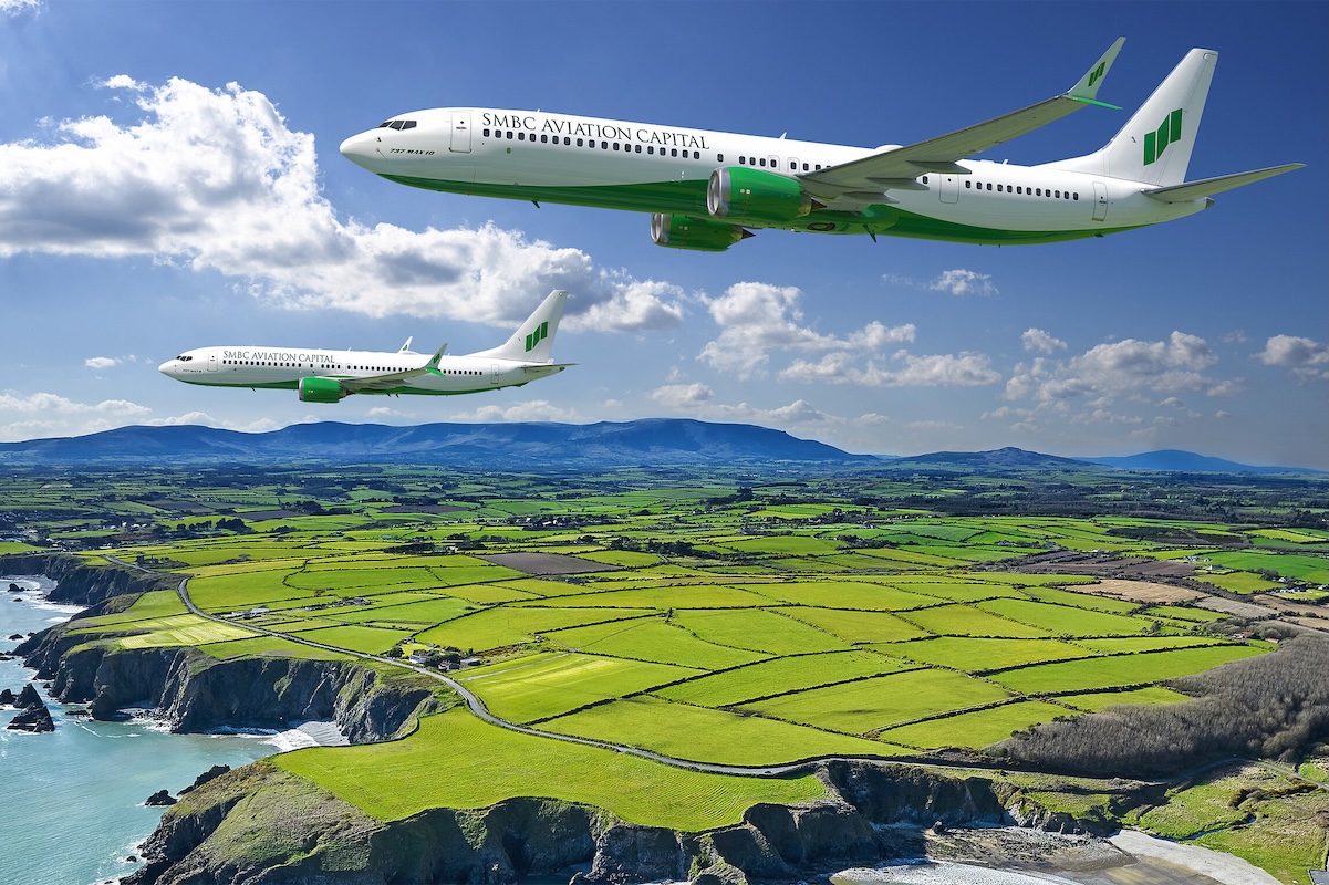 Boeing and SMBC Aviation Two SMBC Aviation Capital airplanes fly in formation over a patchwork green farmland along a rocky coastline under a blue sky