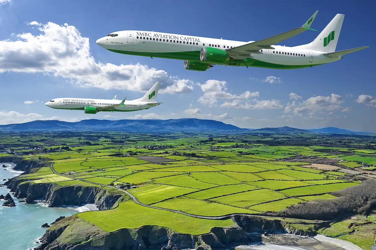 Boeing and SMBC Aviation Two SMBC Aviation Capital airplanes fly in formation over a patchwork green farmland along a rocky coastline under a blue sky