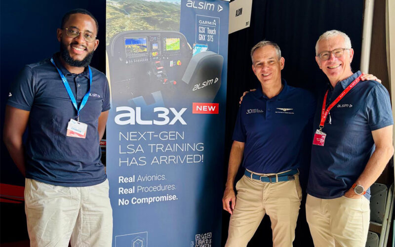 Cirrus Aviation AL3X 1200x800 Three men stand beside a tall banner advertising al3x next gen LSA training at an aviation event