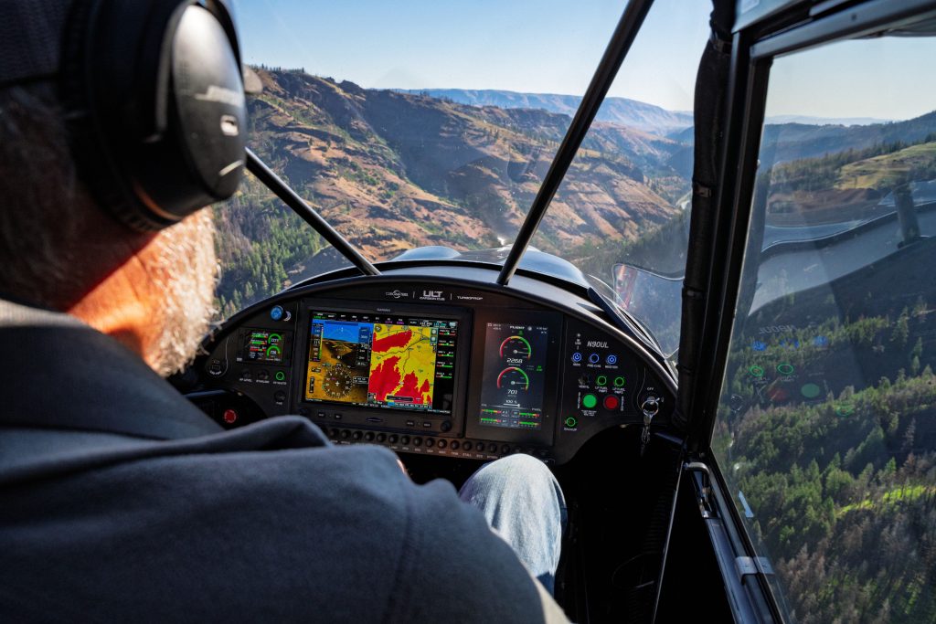 DSC02045 1024x683 Pilot wearing a headset in a small airplane cockpit avionics showing a color navigation map as mountains pass below