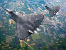 Two stealth bombers flying in formation over patchwork farmland seen from above