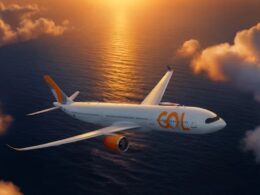 GOL Airlines airliner with orange accents flying over the ocean at sunset viewed from the side in warm light