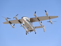 Tilt rotor aircraft with four propellers flying in a clear blue sky landing gear extended