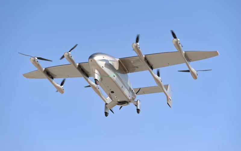 Tilt rotor aircraft with four propellers flying in a clear blue sky landing gear extended