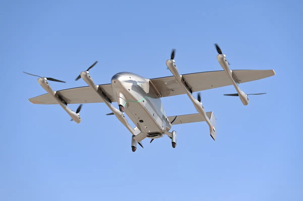 Tilt rotor aircraft with four propellers flying in a clear blue sky landing gear extended