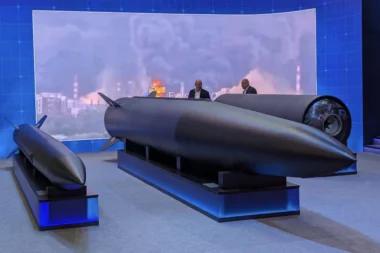 Exhibition display a large dark missile on a stand with two suited figures discussing it blue backdrop reading 18062026 MOSCOW OIL REFINERY