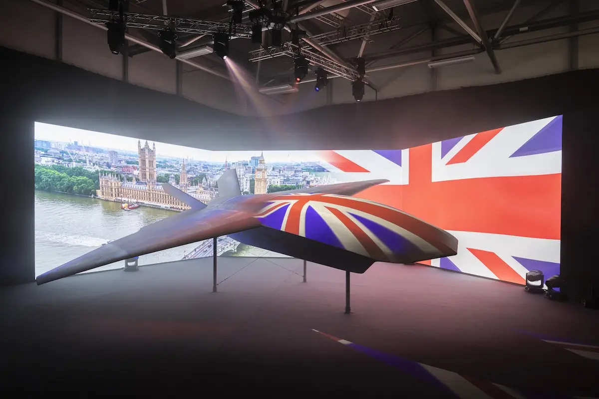 BAE Systems Brontanax Suspended futuristic aircraft on display indoors with a large Union Jack backdrop and cityscape projection behind it