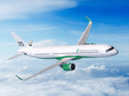 White commercial airplane with green accents and SMBC Aviation Capital logo in flight above clouds