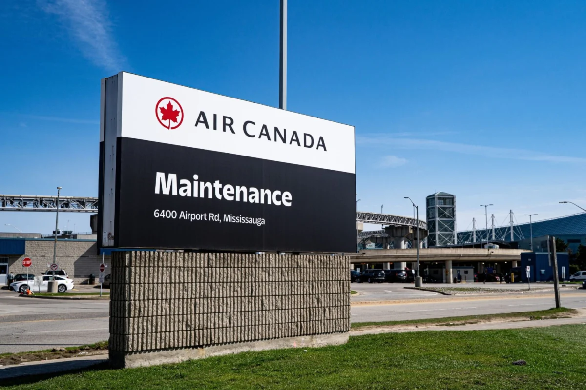Air Canada Maintenance sign at an airport entrance with address 6400 Airport Rd Mississauga under a blue sky