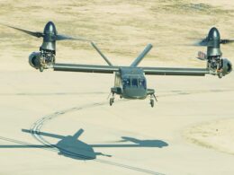 Twin engine tilt rotor aircraft Osprey on a runway with rotors extended preparing to land its shadow is visible on the tarmac