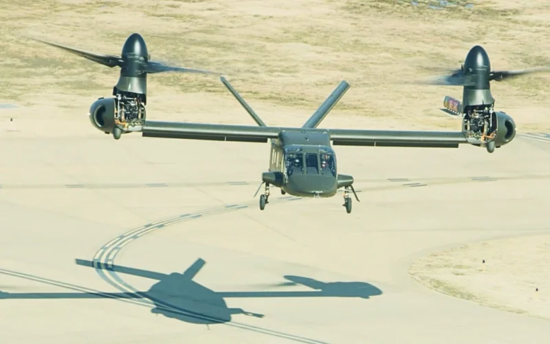 Twin engine tilt rotor aircraft Osprey on a runway with rotors extended preparing to land its shadow is visible on the tarmac